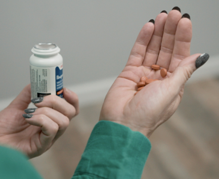 woman's hands holding a pill bottle and pills