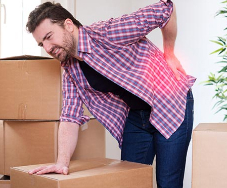 Man suffering from lower back paina after lifting boxes