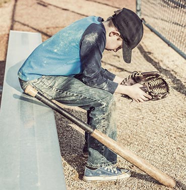 Little boy with a baseball gear, sitting and waiting in sadness